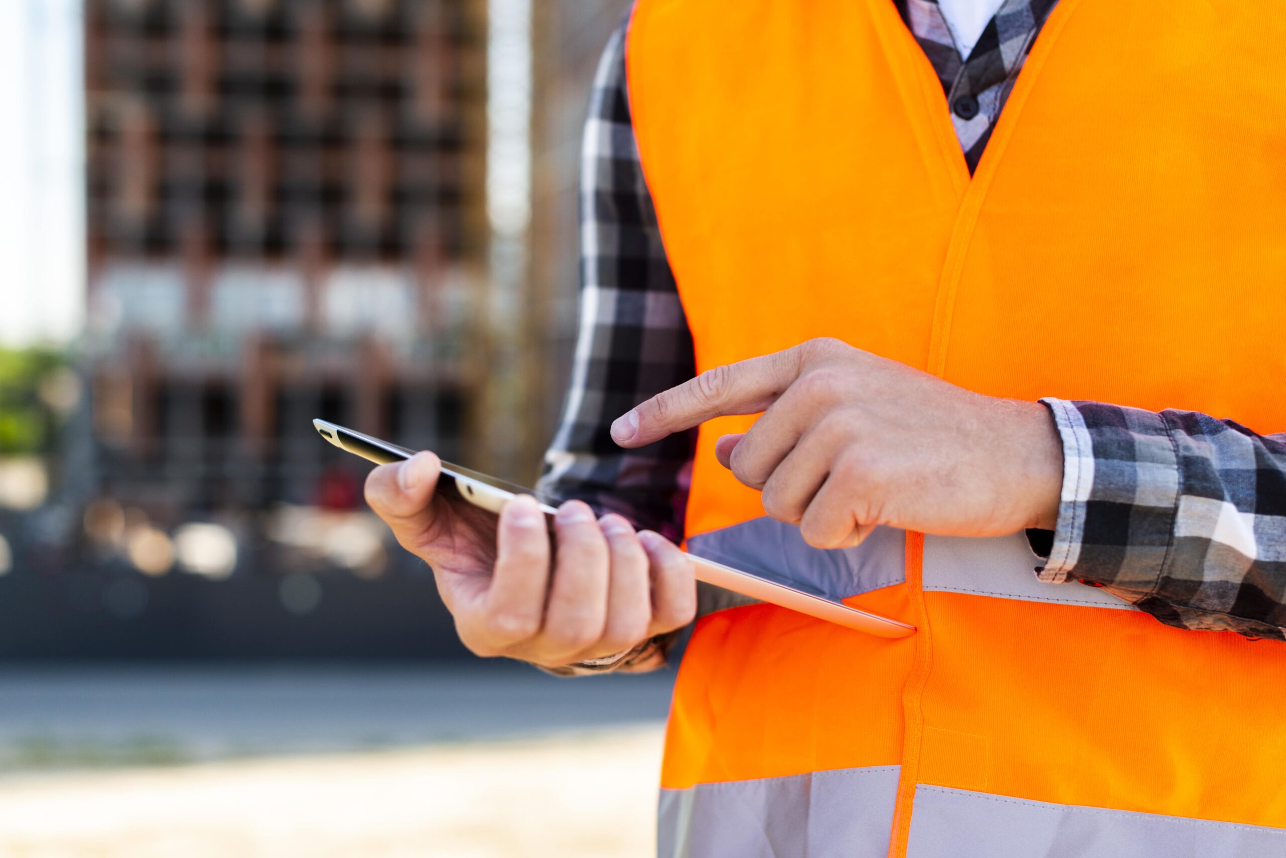 Construction worker in a safety vest checking in on a phone