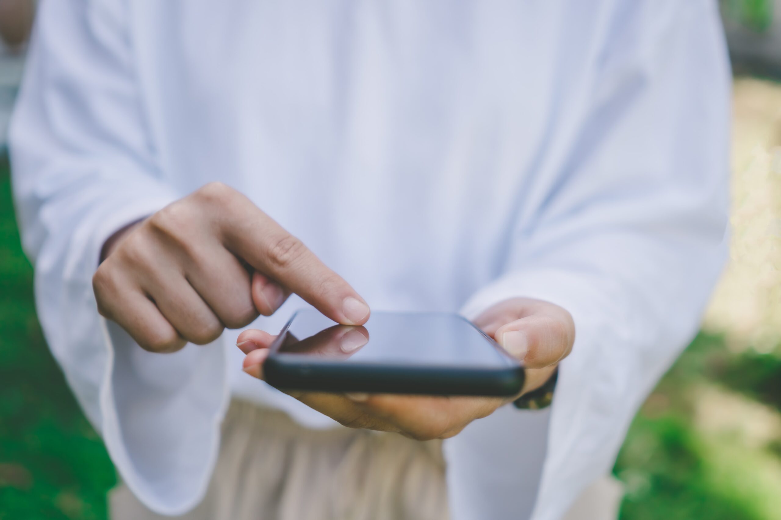 Person in a white robe tapping a smartphone