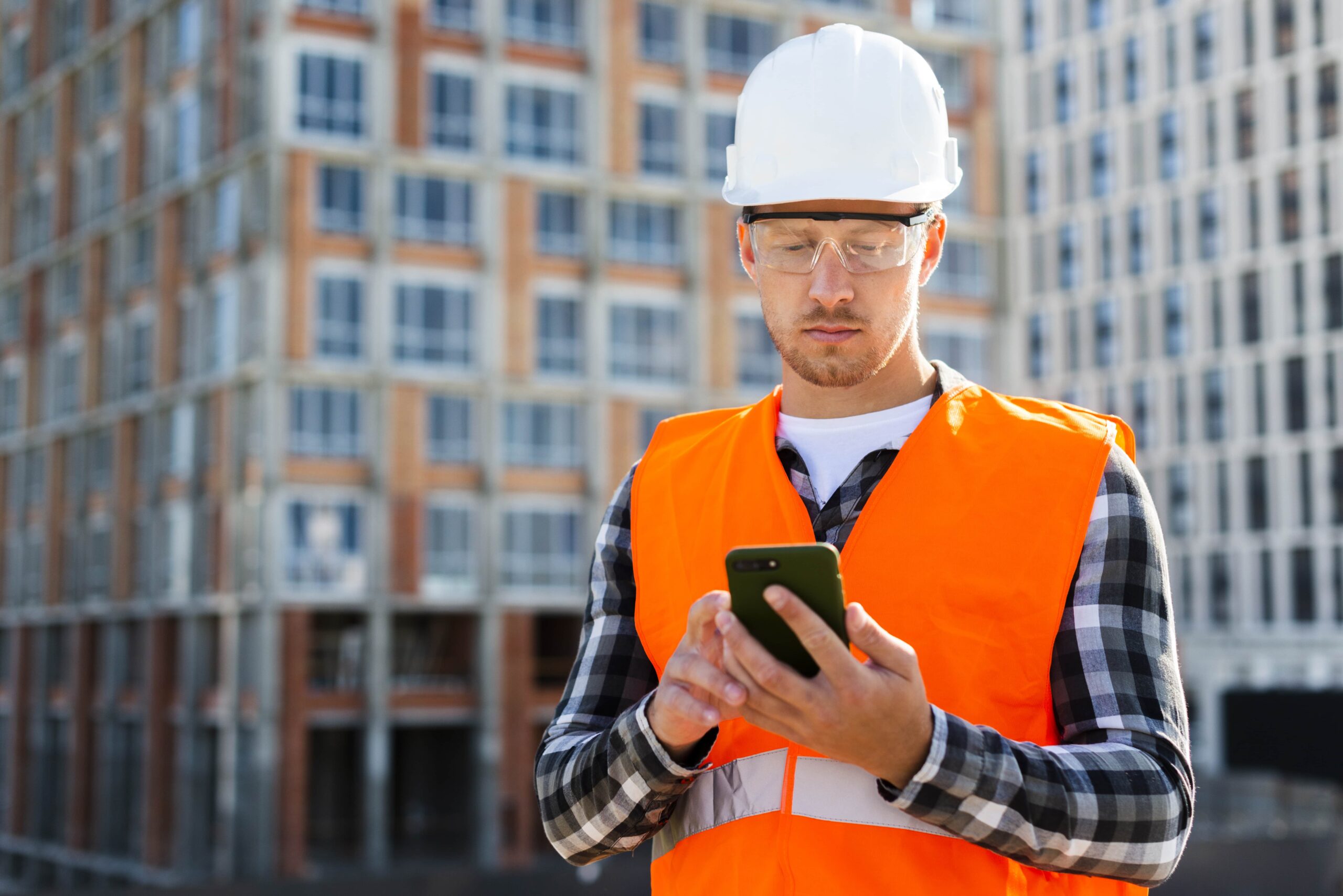 Site worker in a hard hat reading an alert on his phone