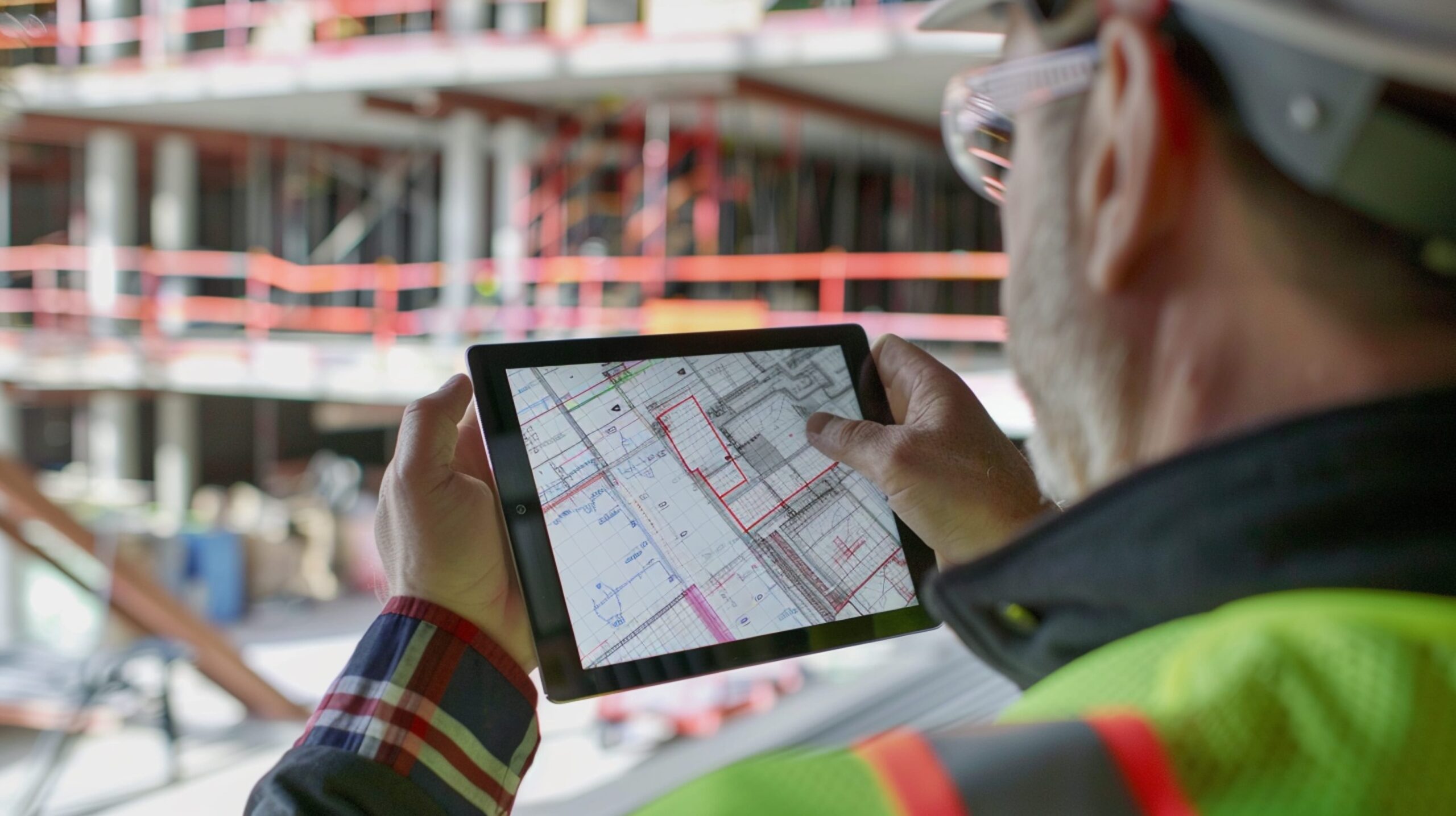 Builder reviewing plans on a tablet at a construction site