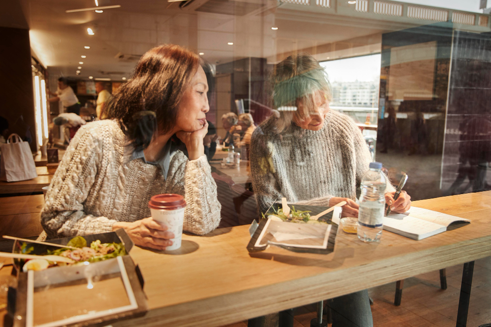 Two women eating takeout meals at a cafe counter