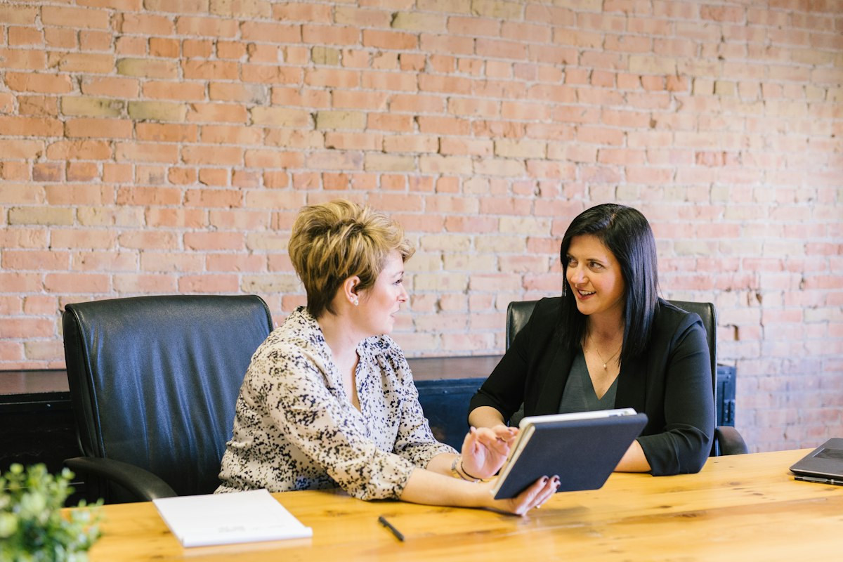 Two professionals discussing app dashboard on tablet
