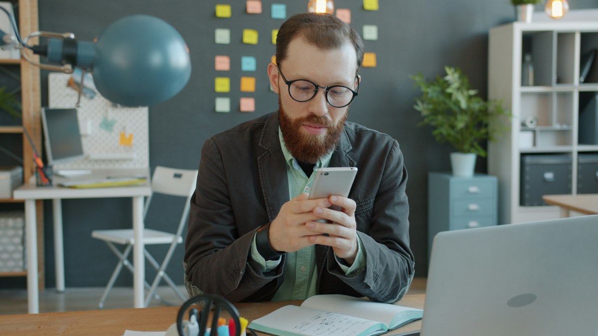 Entrepreneur reviewing mobile app on smartphone at desk